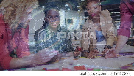 Collaborating group wearing casual attire designing at office table, with markers and AR overlay Collaborating group wearing casual attire designing at office table, with markers and AR overlay 135667884
