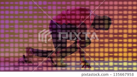 Crouching athlete in red shirt and spikes initiating sprint at studio with gradient grid backdrop Crouching athlete in red shirt and spikes initiating sprint at studio with gradient grid backdrop 135667958