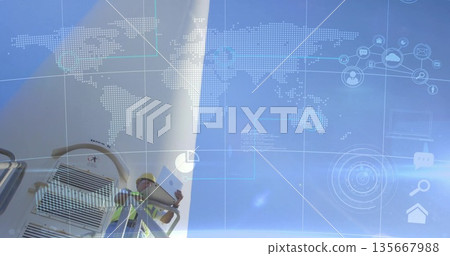 Technician in helmet vest inspecting wind turbine with tablet at farm with data overlay, copy space Technician in helmet vest inspecting wind turbine with tablet at farm with data overlay, copy space 135667988