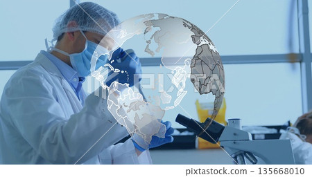 Researcher in lab gear pipetting in lab with test tube, biohazard bin, digital globe graphic 135668010