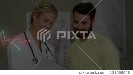 White-coated physician and patient examining clipboard in exam room, with stethoscope and charts 135668048