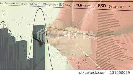 Using smartphone and credit card, man in salmon sweater in office, charts and ticker, copy space 135668059