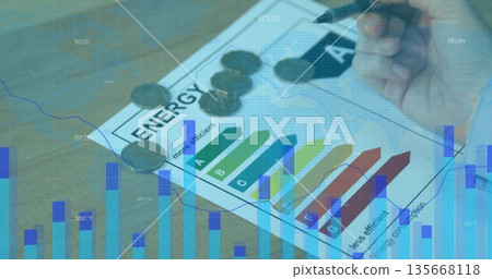 Analyzing right hand marking energy efficiency rating sheet on desk, with coins and chart overlays 135668118