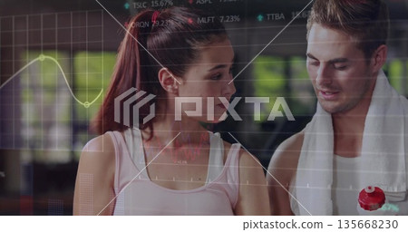 Discussing workout partners in sportswear analyzing performance data in gym, with data overlay Discussing workout partners in sportswear analyzing performance data in gym, with data overlay 135668230