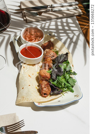 Lamb shashlik served with flatbread and herbs 135668272