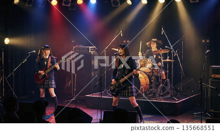 一支高中女子搖滾樂團在聚光燈下激情演唱和表演。 135668551