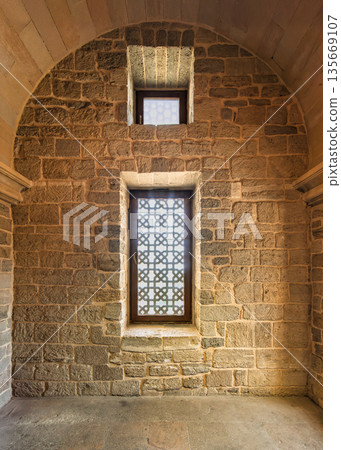 Historic stone wall with intricate geometric windows and arched ceiling inside Palace of the Shirvanshahs, Baku, Azerbaijan. 135669107