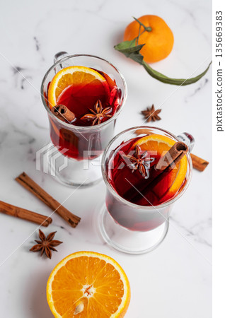 Two glasses of mulled wine, orange, cinnamon, and star anise on a marble background with spice Two glasses of mulled wine, orange, cinnamon, and star anise on a marble background with spice 135669383