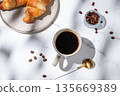 Freshly brewed black coffee in a cup on a white marble background with croissants 135669389