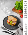 Sandwich with ham, cheese, lettuce and vegetable on a black plate on a concrete table 135669393