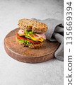 Sandwich with ham, cheese, lettuce and vegetable on a wooden board on a gray concrete background 135669394