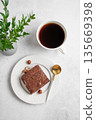 Piece of chocolate brownie on a plate and a cup of espresso coffee on a light background 135669398