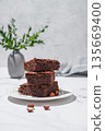 Chocolate brownie on a plate on a marble background with nuts branch and morning shadow. 135669400