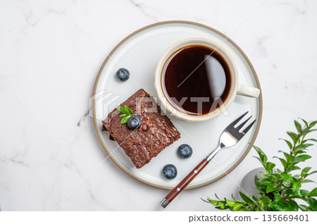 Chocolate brownie on a plate and a cup of espresso coffee on a marble background Chocolate brownie on a plate and a cup of espresso coffee on a marble background 135669401
