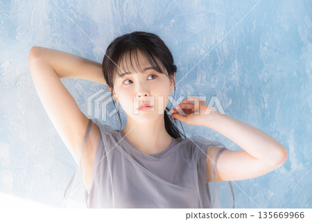 Close-up of a woman posing in sunlight against a light blue background Close-up of a woman posing in sunlight against a light blue background 135669966