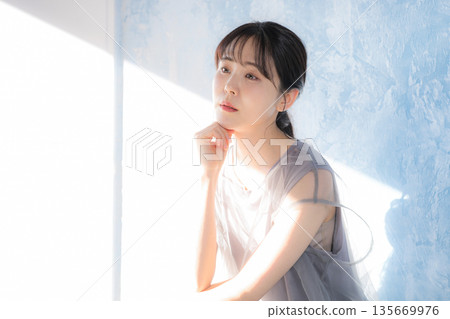 Profile of a woman posing in sunlight against a light blue background, thinking pose Profile of a woman posing in sunlight against a light blue background, thinking pose 135669976