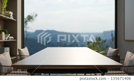 Empty wooden table and metal armchairs aside bookshelf and window wall with outside nature scenery. Empty wooden table and metal armchairs aside bookshelf and window wall with outside nature scenery. 135671406