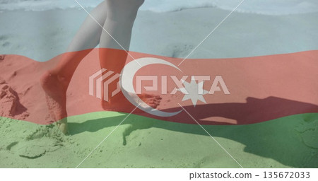 Walking bare lower legs and feet along sandy beach shoreline, with Azerbaijan flag overlay 135672033