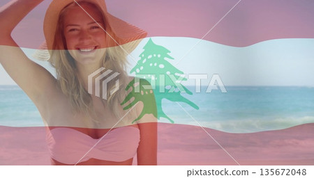Smiling woman wearing straw sunhat, bikini top on sandy beach, Lebanese flag overlay, copy space 135672048