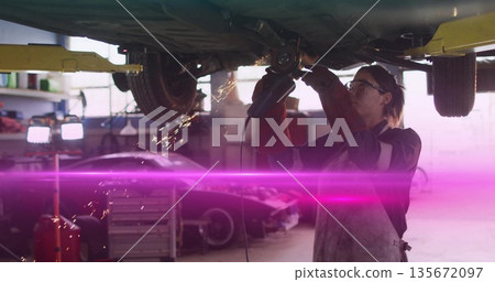 Grinding woman mechanic using grinder under car lift in garage with sparks, copy space Grinding woman mechanic using grinder under car lift in garage with sparks, copy space 135672097