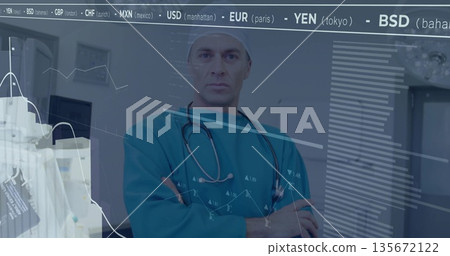Standing doctor in teal scrubs crossing arms in exam room, with stethoscope, monitor, data overlays 135672122