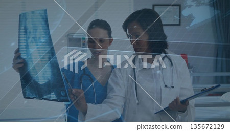 Reviewing chest X-ray film staff wearing scrubs, lab coat in hospital exam room, with stethoscopes Reviewing chest X-ray film staff wearing scrubs, lab coat in hospital exam room, with stethoscopes 135672129