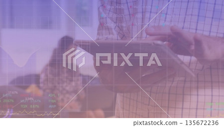 Displaying analyst holding tablet and overlaying stock tickers in office, with blurred coworkers Displaying analyst holding tablet and overlaying stock tickers in office, with blurred coworkers 135672236