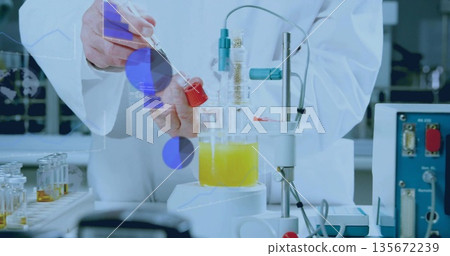 Scientist wearing lab coat holding test tube above yellow beaker on stir plate at bench, cables 135672239