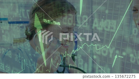 Doctor in scrubs listening with stethoscope at monitors in clinic, colleague viewing green charts 135672275