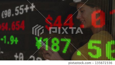 Using smartphone woman in blazer on trading floor, LED ticker showing currency rates, copy space Using smartphone woman in blazer on trading floor, LED ticker showing currency rates, copy space 135672336