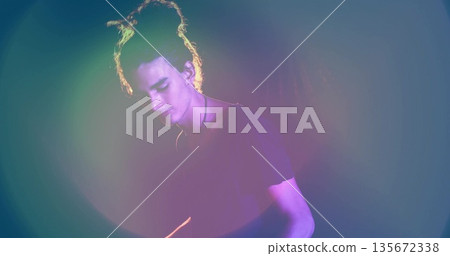Standing male performer basking under multicolored spotlights in studio, with simple cord necklace Standing male performer basking under multicolored spotlights in studio, with simple cord necklace 135672338