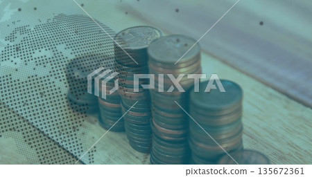 Rising copper coin stacks occupying wooden office desk, featuring dotted world map overlay 135672361