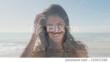 Featuring smiling white woman in red top touching hair on shoreline, with dancing couple in surf 135672388