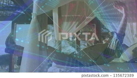 Reclining senior man raising arms on canopy bed overlooking trees on veranda, with holographic data Reclining senior man raising arms on canopy bed overlooking trees on veranda, with holographic data 135672389