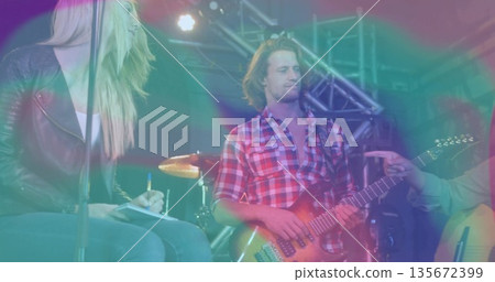 Playing electric guitar, guitarist wearing red shirt on concert stage with drums and trusses Playing electric guitar, guitarist wearing red shirt on concert stage with drums and trusses 135672399