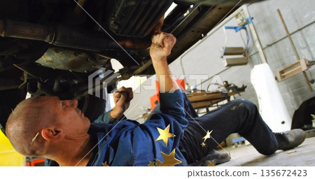 Holding wrench, mechanic wearing coveralls tightening suspension under vehicle at garage with cart Holding wrench, mechanic wearing coveralls tightening suspension under vehicle at garage with cart 135672423