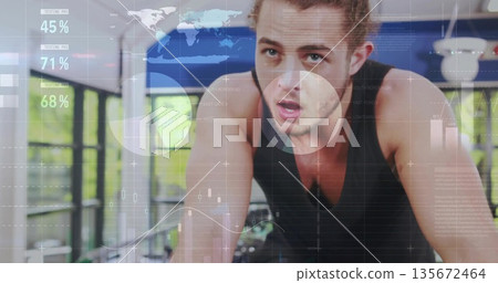 Cycling fit male leaning forward intensely at modern gym with bike and digital analytics overlays 135672464