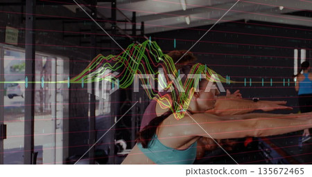 Performing six adults executing synchronized squats inside gym, with rig and waveform overlay 135672465