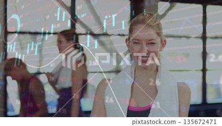 Smiling fitness enthusiast posing in fitness studio with white towel and teenage girls near windows 135672471