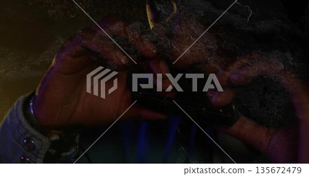 Denim-shirted musician playing harmonica on stage under purple amber lighting, grainy overlay 135672479