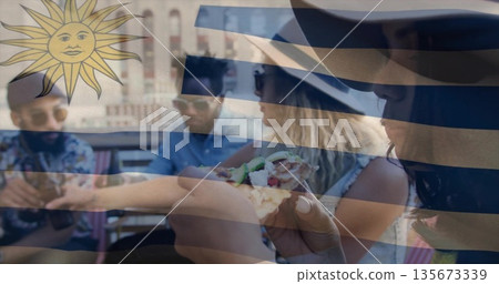 Eating group of friends sharing pizza at rooftop terrace table, wearing sunglasses and sun hat 135673339