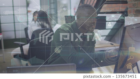 Interacting African American man reaching for touchscreen in modern office with digital overlays 135673451