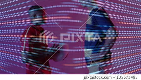 Standing two men wearing jerseys facing off in studio, holding ball with digital dot projection Standing two men wearing jerseys facing off in studio, holding ball with digital dot projection 135673485