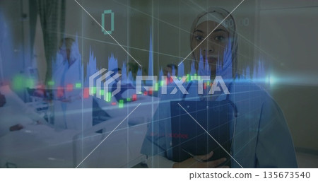 Holding clipboard nurse in scrubs checking monitor at hospital ward, with financial overlay Holding clipboard nurse in scrubs checking monitor at hospital ward, with financial overlay 135673540