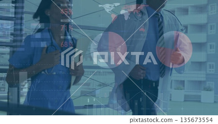 Walking scrub-clad nurse and suited doctor analyzing digital charts in corridor with stethoscopes 135673554