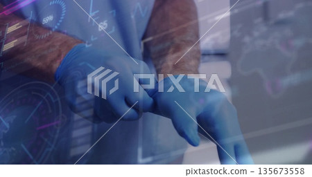 Doctor wearing blue scrubs pulling glove onto hand in hospital room, with medical data overlay Doctor wearing blue scrubs pulling glove onto hand in hospital room, with medical data overlay 135673558