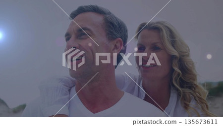 Embracing couple gazing toward left at seaside beach during sunrise, wearing casual white clothing Embracing couple gazing toward left at seaside beach during sunrise, wearing casual white clothing 135673611