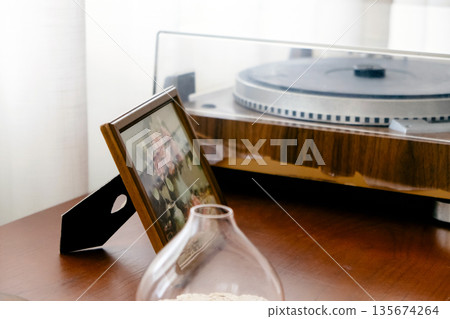 Vintage vinyl record player on the table with a picture frame Vintage vinyl record player on the table with a picture frame 135674264