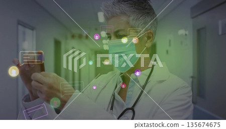 Viewing doctor tapping smartphone under hospital lights, with floating chat icons and stethoscope 135674675