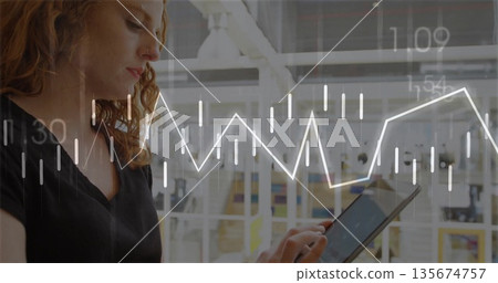 Red-haired woman in black top analyzing financial charts on tablet in glass office, copy space Red-haired woman in black top analyzing financial charts on tablet in glass office, copy space 135674757